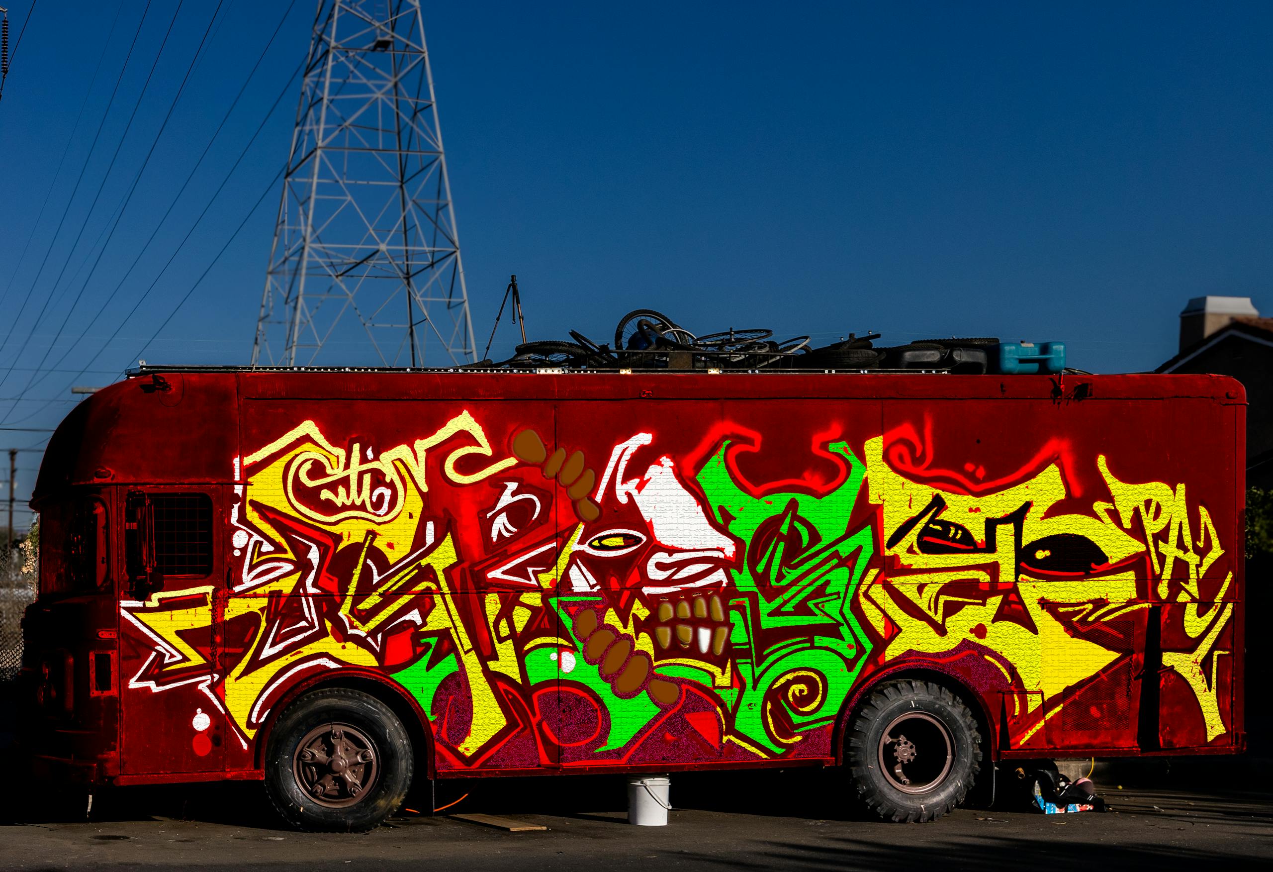 Vibrant graffiti artwork covering a parked red bus in an urban outdoor setting.